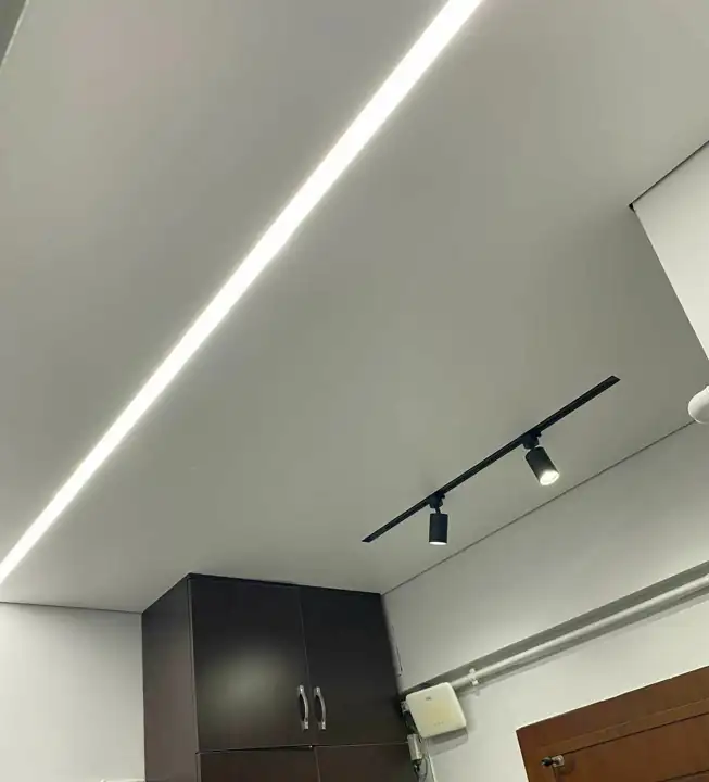 Linear light and track lighting integrated into a stretch ceiling